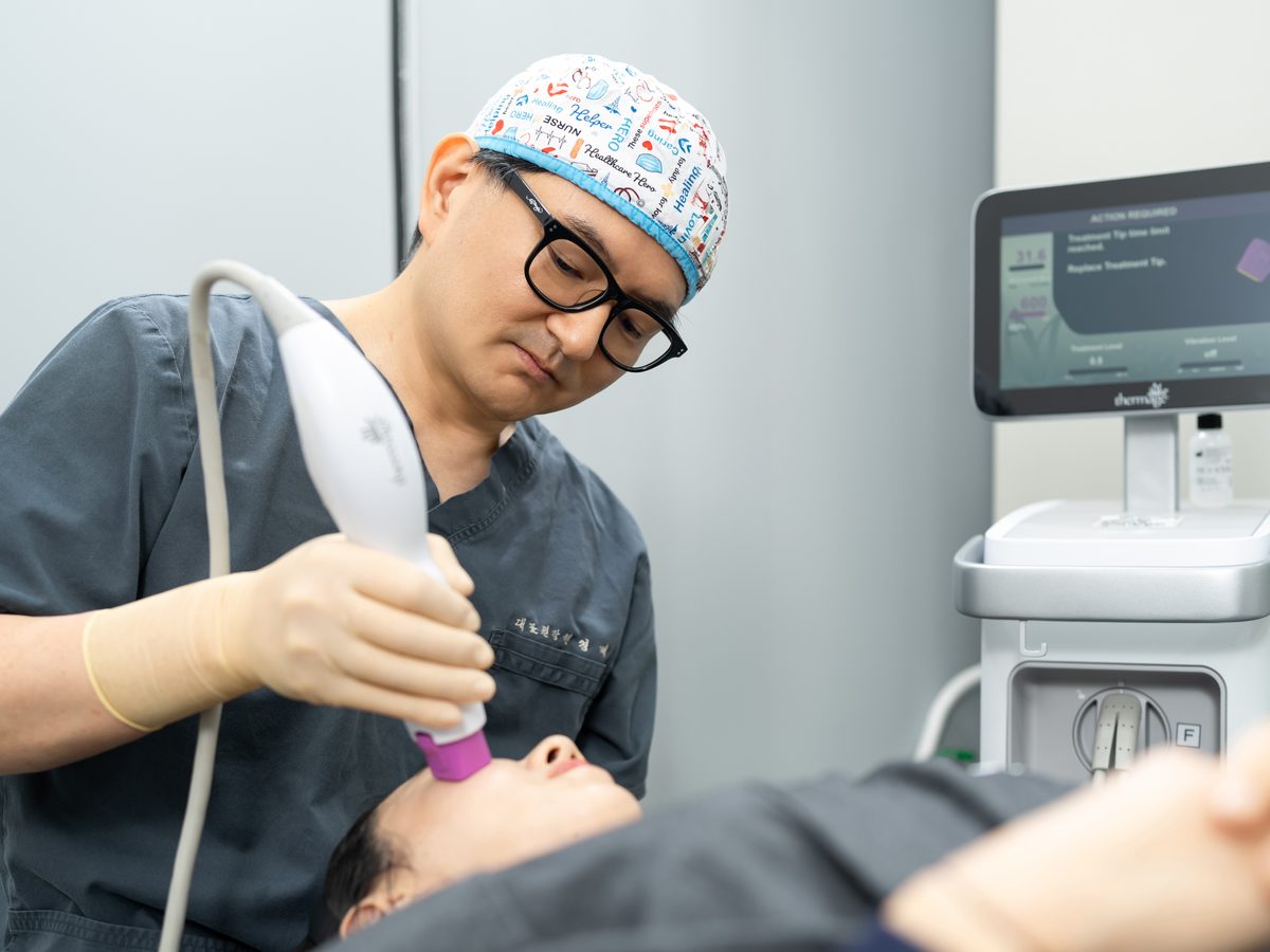 醫師手持 Thermage FLX 探頭為躺著的患者進行臉部療程
